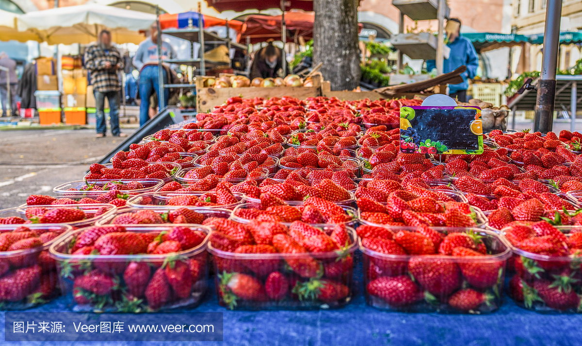 在农贸市场的零售展示上,近距离观察新鲜的红草莓在塑料容器中的木箱,高角度观看